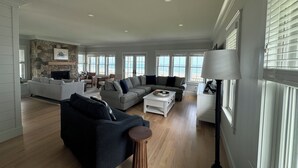 A spacious living room with a fireplace, large windows, and a stone accent wall. - Brand new Five bedroom beachfront home on Moody Beach...Amazing location! (Wells)