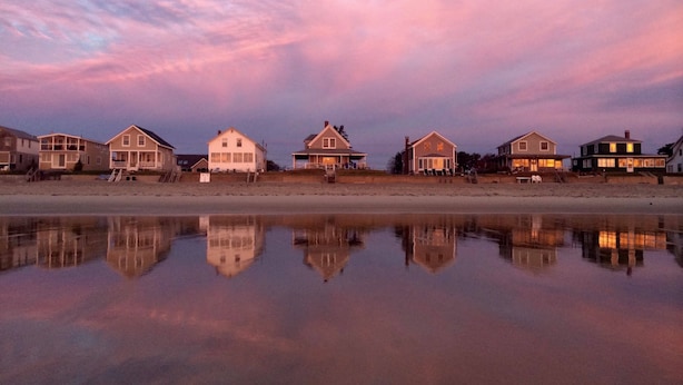 A beachfront property with multiple houses aligned along the shore, reflecting in calm waters. - Brand new Five bedroom beachfront home on Moody Beach...Amazing location! (Wells)