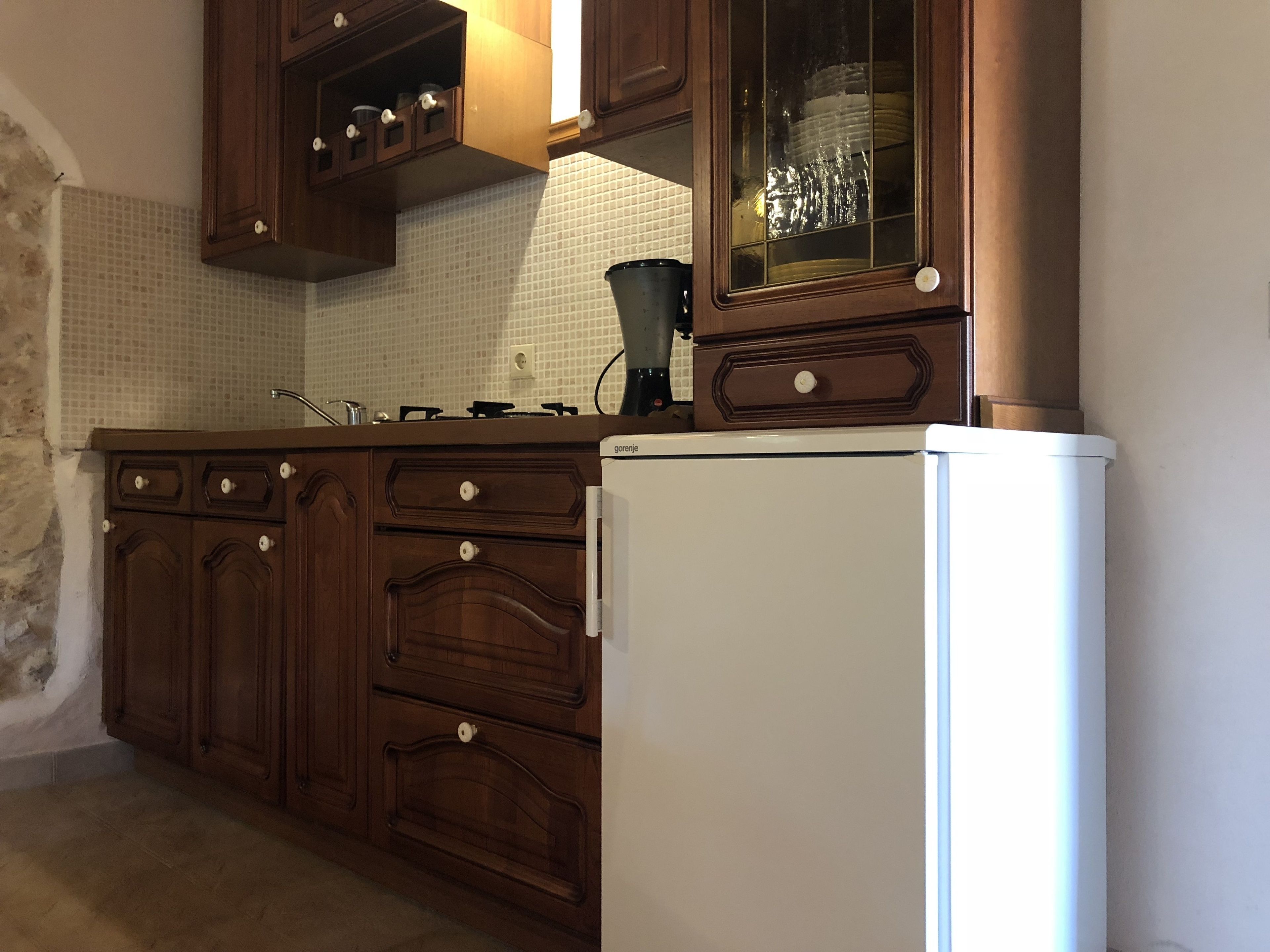 A kitchen with wooden cabinets, a white refrigerator, and a tiled backsplash.