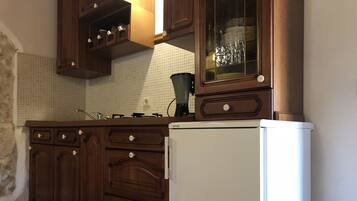 A kitchen with wooden cabinets, a white refrigerator, and a tiled backsplash.