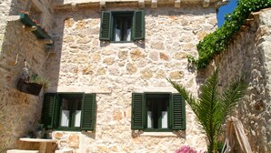 Un edificio de piedra con dos ventanas y un pequeño balcón.