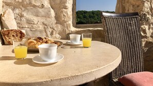 Una mesa redonda con alimentos para el desayuno, dos tazas y un vaso de jugo de naranja.