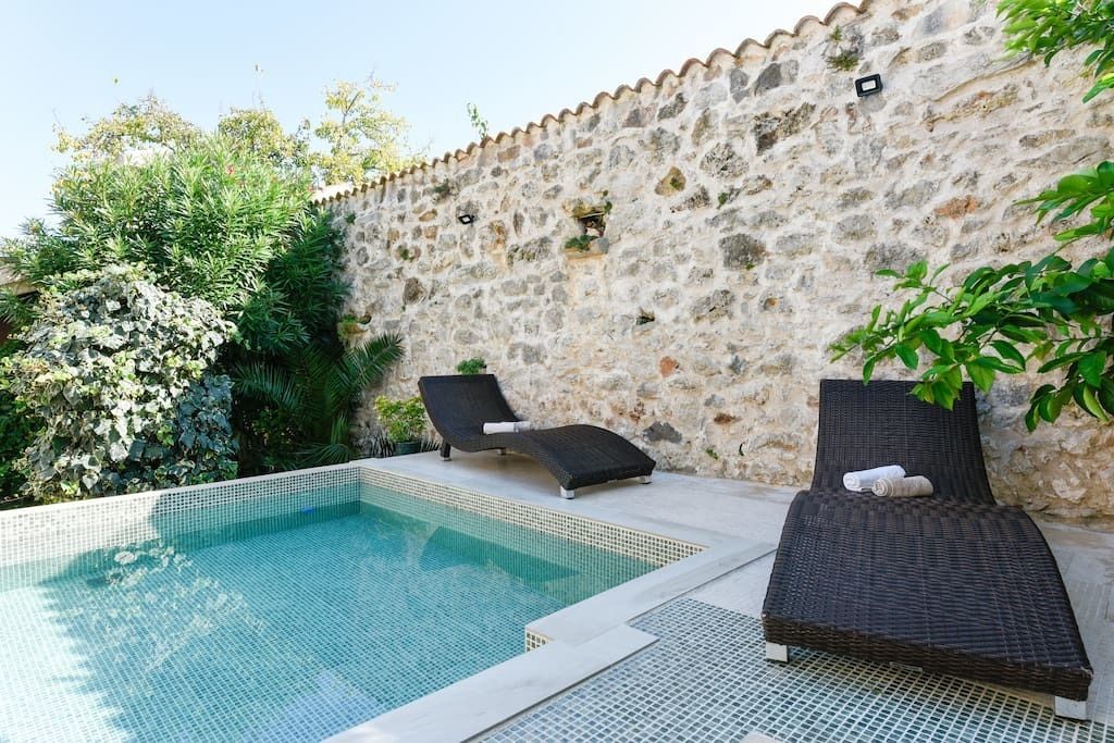 Une piscine avec deux chaises longues et un mur en pierre.
