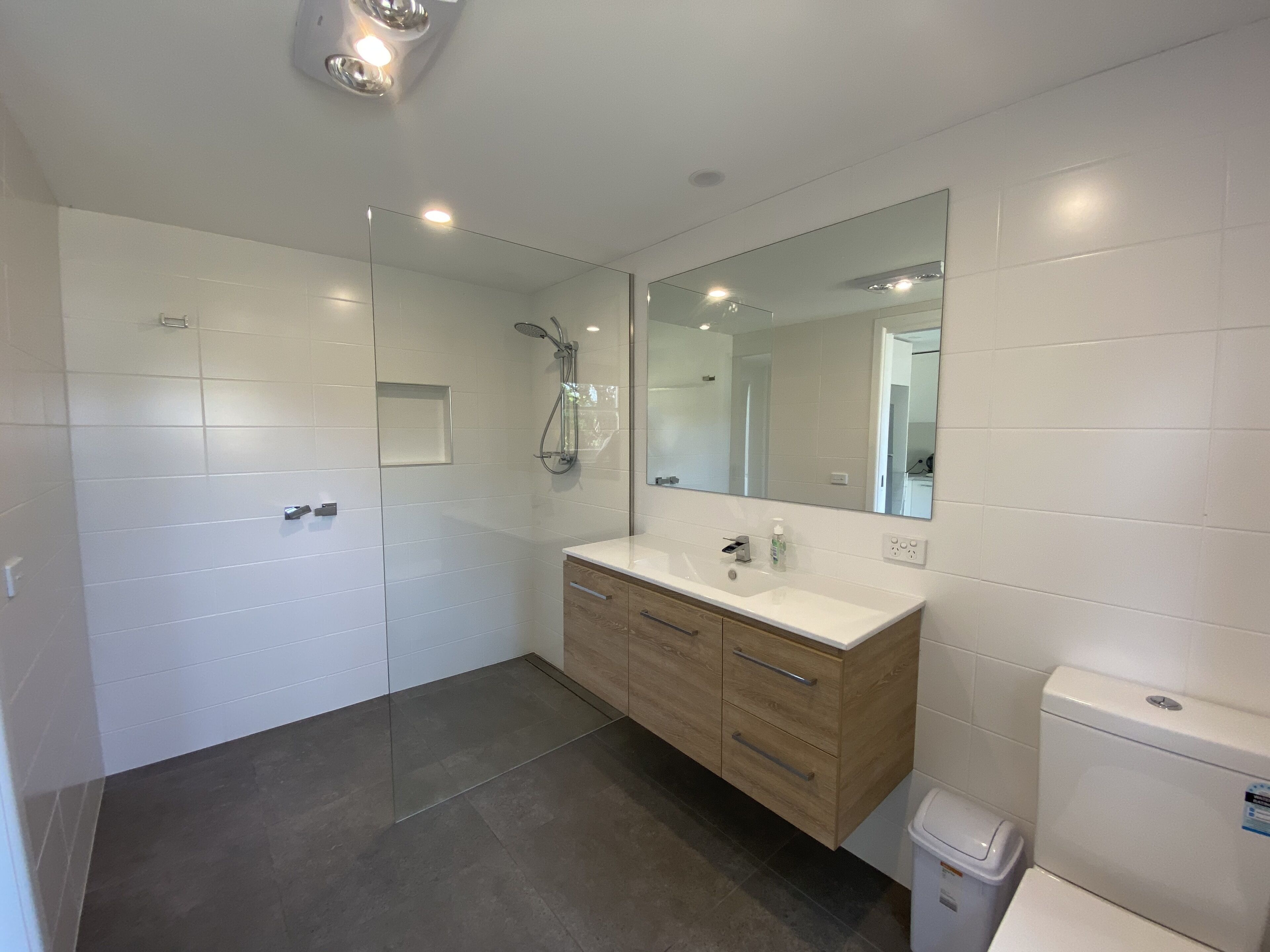 A modern bathroom with a glass shower enclosure, a vanity with a mirror, and a toilet.