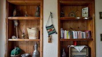 Une pièce avec des étagères en bois où sont rangés des livres, des objets de décoration et une radio ancienne.