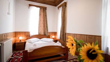 A wooden-framed bed with white linens, two bedside lamps, and a floral-patterned curtain.
