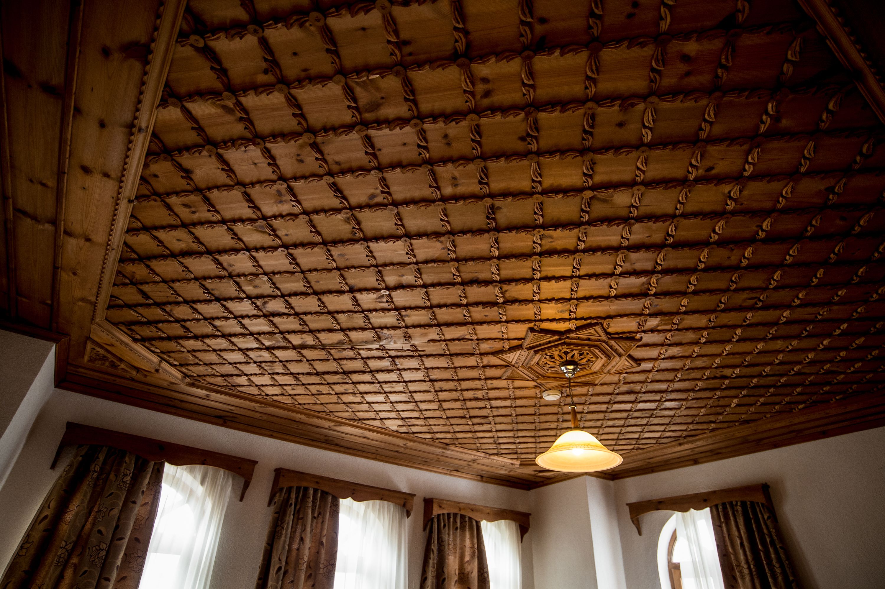 A room with a wooden ceiling featuring a grid pattern and a central light fixture.