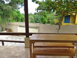 Enjoy a meal on the balcony with a view of the lush garden and a nearby building.