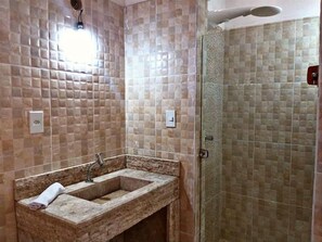 Bathroom features a rectangular sink with a countertop and a single faucet, a glass-enclosed shower area, and a light fixture on the wall.