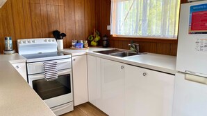 A compact kitchen with a stove, oven, sink, and a refrigerator.