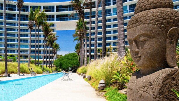 A modern hotel with a pool, palm trees, and a Buddha statue. - Spectacular Beach front 2 Bedroom Condo (Riviera Nayarit)