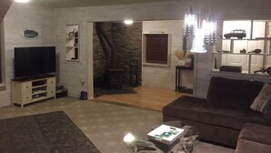 Una sala de estar con televisor, sofá, mesa de centro y chimenea.