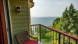 Un balcone con mobili in vimini, un tavolo in vetro e vista sull'oceano.
