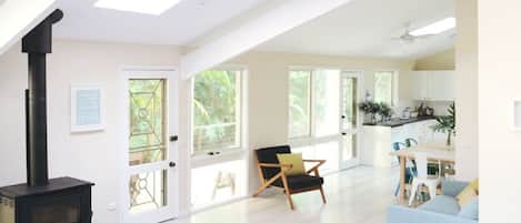 A spacious living area with a black wood-burning stove, a blue sofa, and a wooden chair.