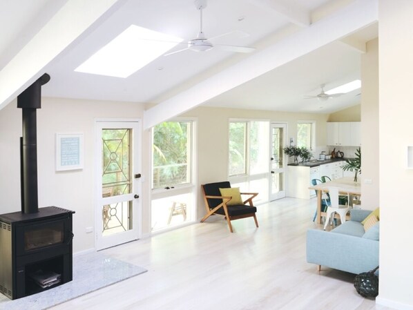 A spacious living area with a black wood-burning stove, a blue sofa, and a wooden chair.