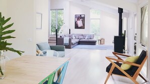 Uma sala de estar espaçosa com uma mesa de jantar de madeira, um sofá e uma lareira.