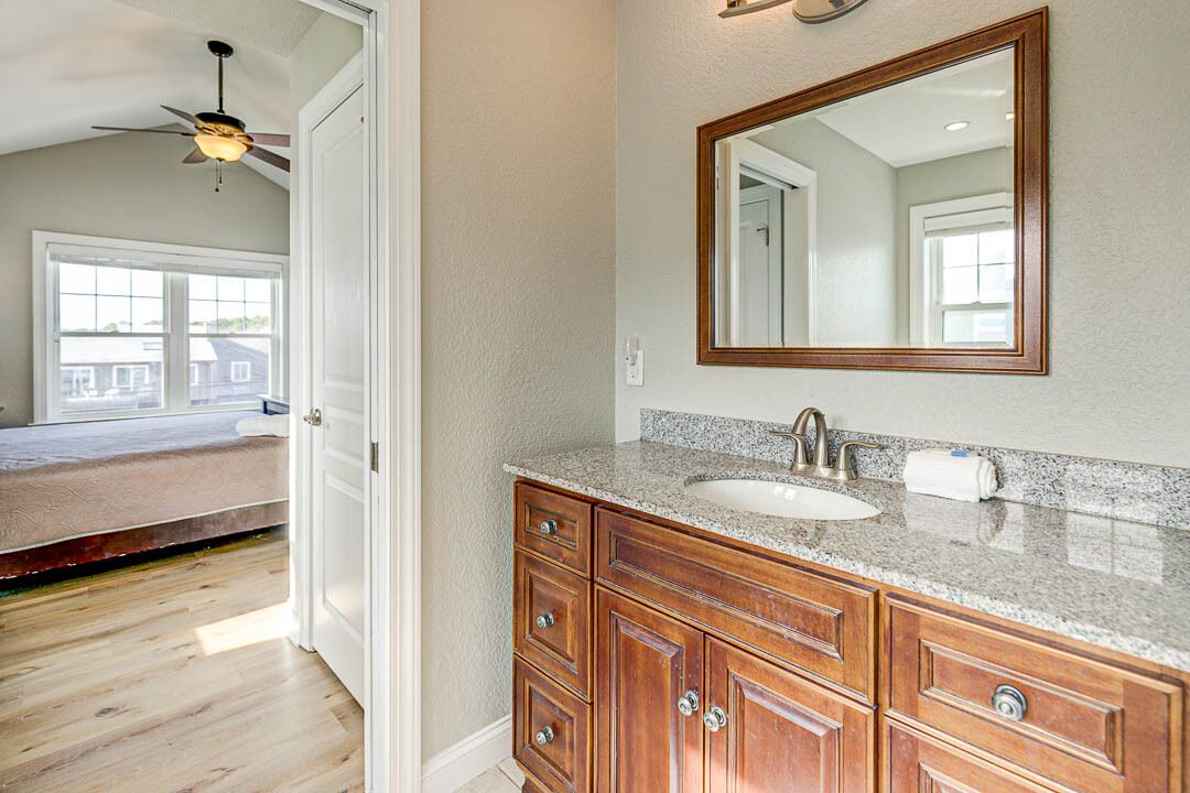 A bathroom with a wooden vanity, a large mirror, and a ceiling fan.