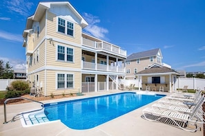 A multi-story house with a swimming pool and outdoor seating area.