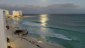 A beach with ocean waves, a clear sky, and buildings in the background. - Beachfront resort in best location, walk to best clubs and restaurants (Cancún)