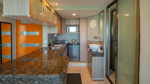 A modern kitchen with granite countertops, stainless steel appliances, and a large window. - Beachfront resort in best location, walk to best clubs and restaurants (Cancún)