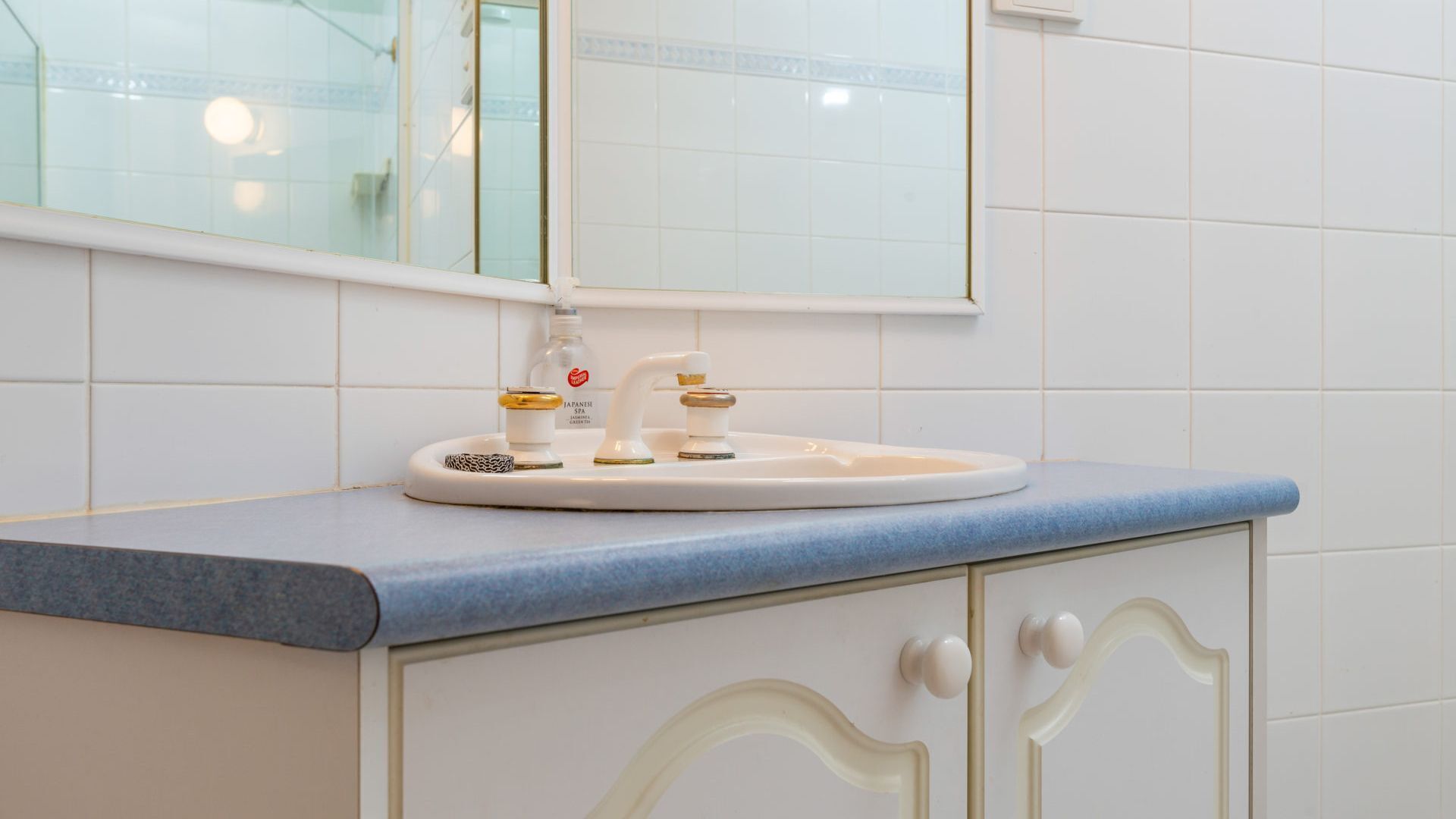 A bathroom with a white sink, a mirror, and a blue countertop.