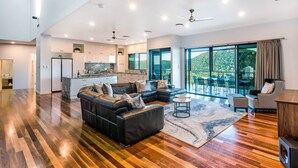 A spacious living area with a modern kitchen, a large dining table, and a balcony with a scenic view.