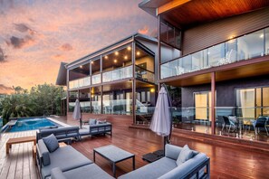 A modern house with a pool, outdoor seating, and a large glass balcony. - Southwinds, Stunning 8 Bedroom House on Hamilton Island (Hamilton Island)