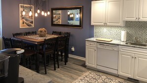 Una cucina moderna con mobili bianchi, un tavolo da pranzo con sedie e un lampadario.