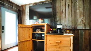 A compact kitchen with wooden cabinetry, a built-in oven, and a coffee maker. - Tree Fort Balcony Suite (Springfield)