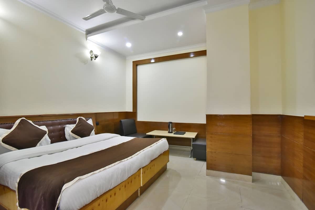 A hotel room with a large bed, a desk, and a chair.