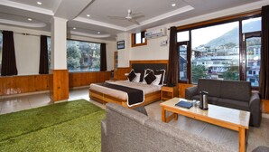 A hotel room with a bed, sofa, and a view of a mountainous landscape. -  The Posh Hotel near Mall Road with Hassle Free Covered Parking (Dharamshala)