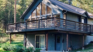 A modern two-story cabin with a balcony, large windows, and a wooden deck. - Tree Top Cabin with access to Flathead Lake (Rollins)