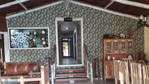 Una habitación amplia con techo alto, una escalera de madera, un espejo con adornos florales y un aparador de madera con puertas de cristal.