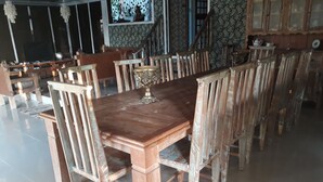 Un comedor con una mesa y sillas de madera, un centro de mesa decorativo de latón y un papel tapiz estampado.