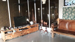 Una sala de estar con un mueble de madera para entretenimiento, un televisor y un sofá.