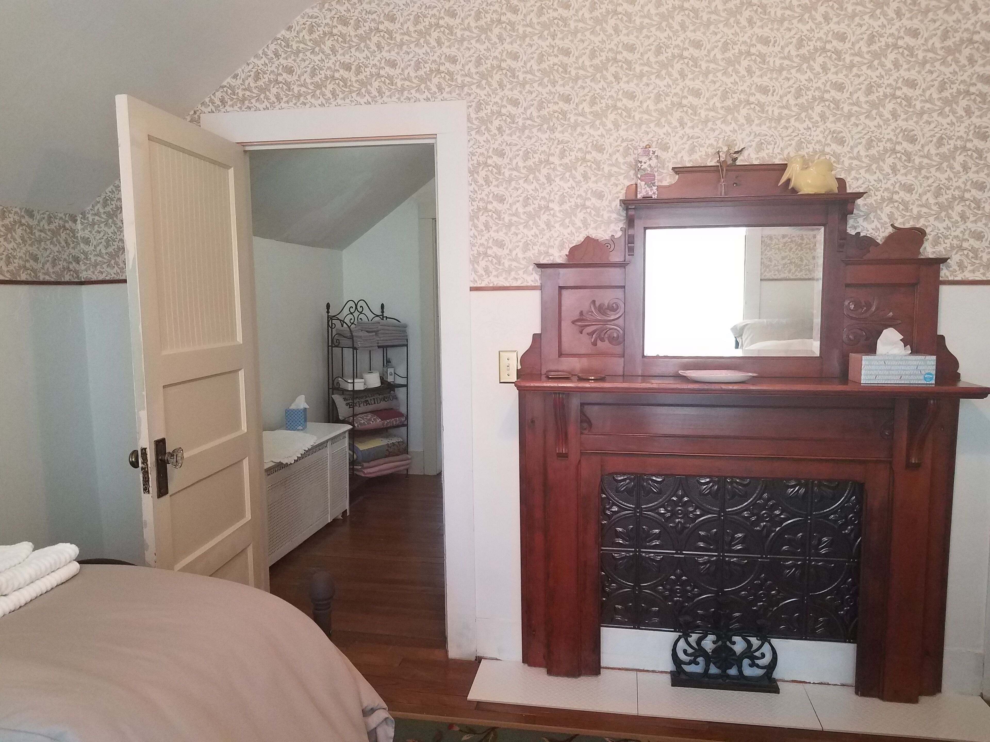 Una camera da letto con un comò in legno, uno specchio e un letto con copripiumino bianco.