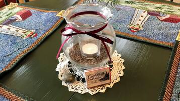A glass jar with a candle and a doily on a table with a patterned tablecloth.