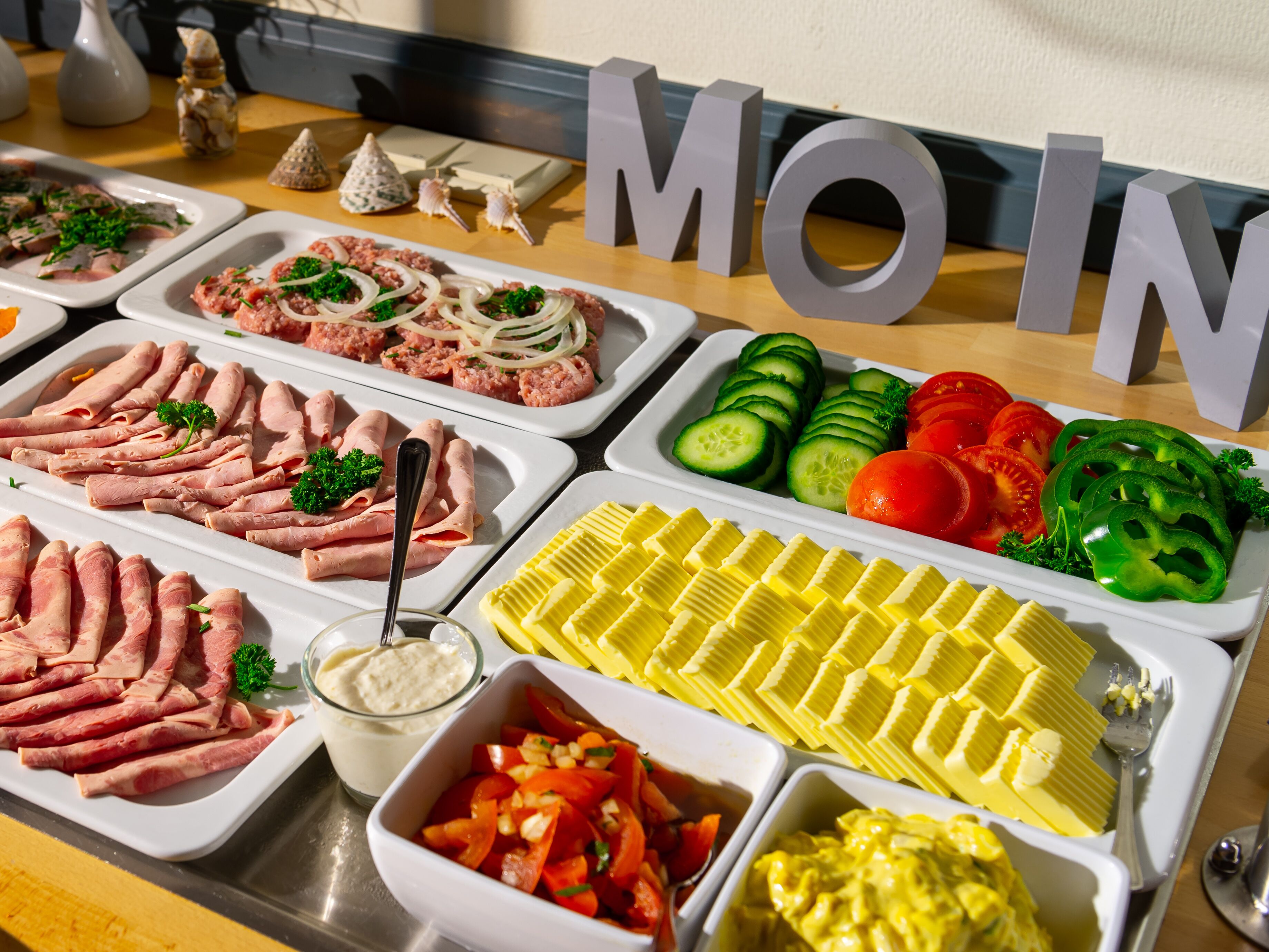 Un bufé con diversas opciones de comida, incluyendo carnes, verduras y salsas.