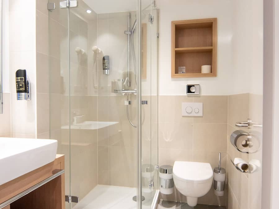 A modern bathroom with a glass-enclosed shower, a white sink, and a wooden vanity.