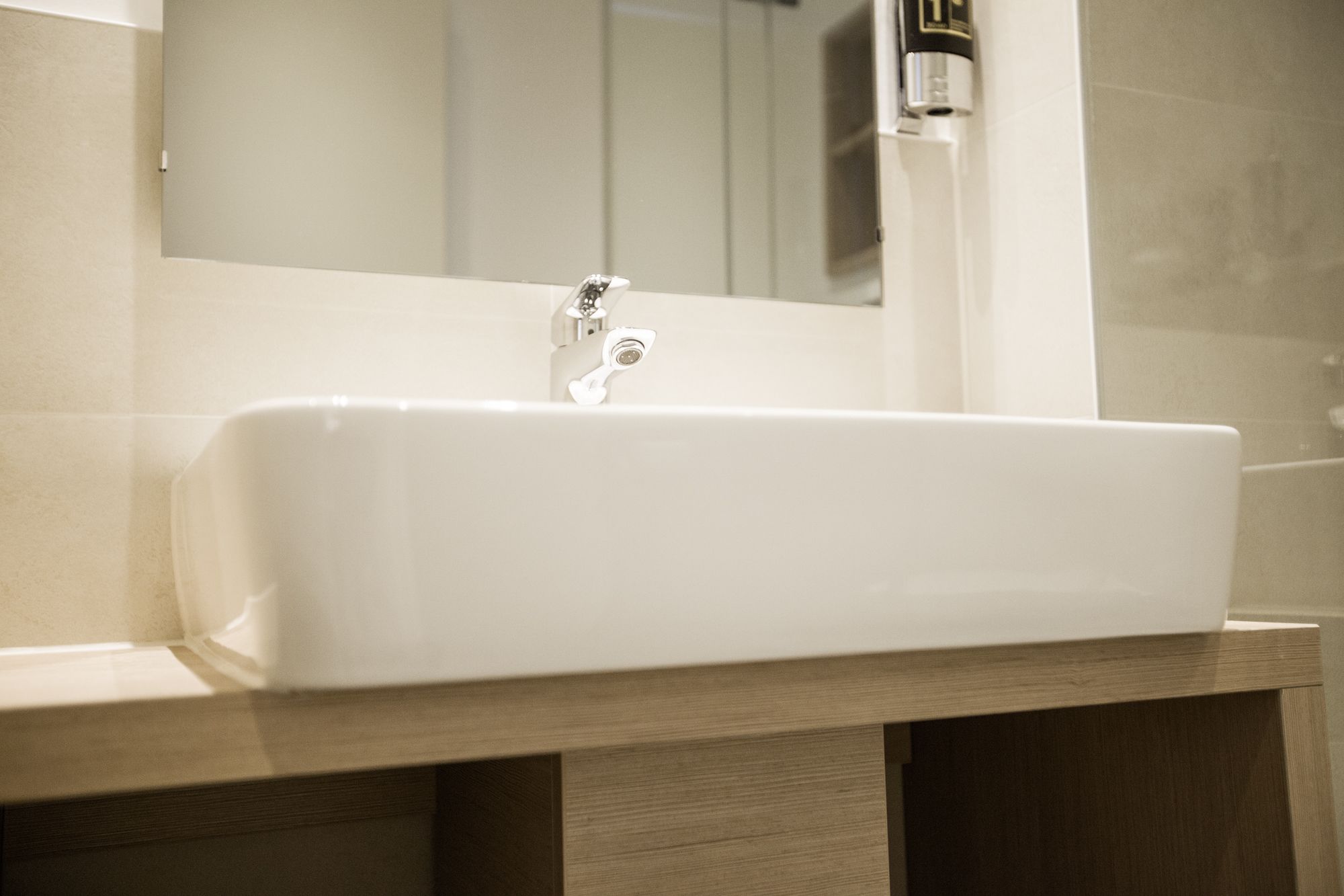 Ein Badezimmer mit einem weißen Waschbecken, einem Spiegel und einer Holzausstattung.