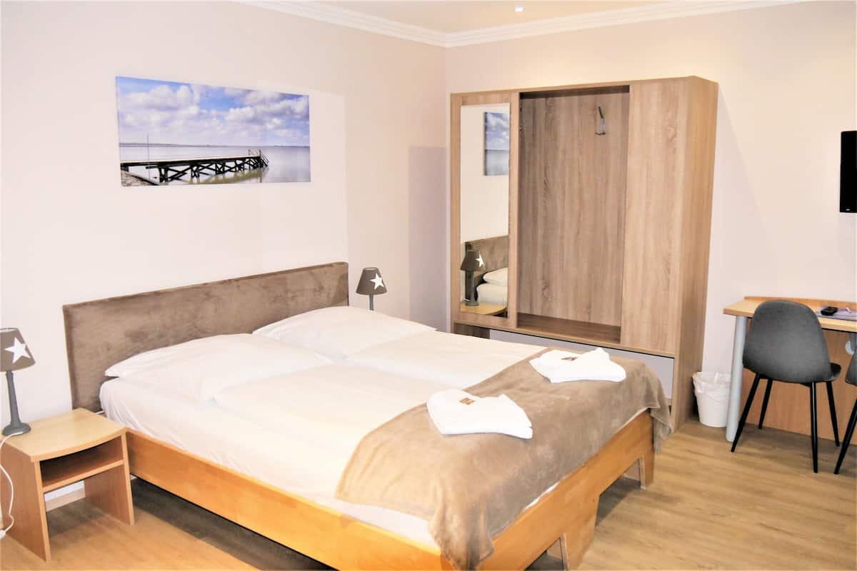 A bedroom with a bed, bedside tables, a desk, and a chair.