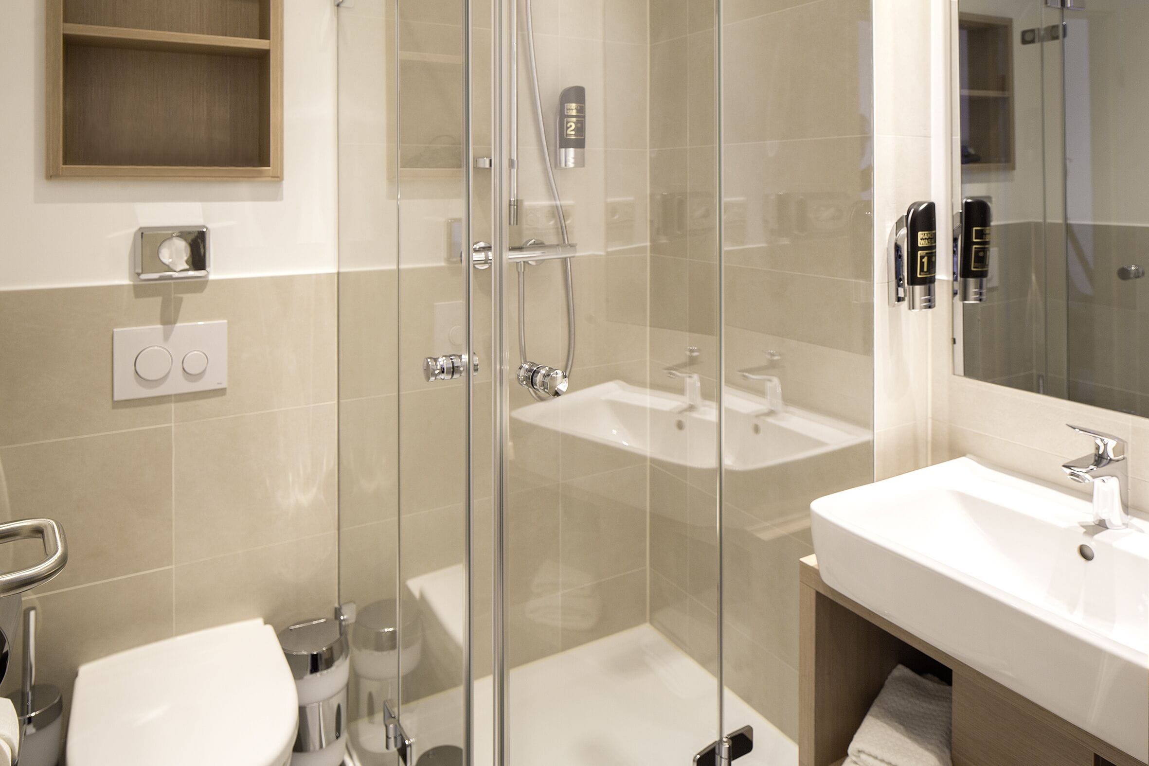 Ein modernes Badezimmer mit einer gläsernen Duschkabine, einem weißen Waschbecken und einer Toilette.