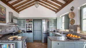 A kitchen with light blue cabinets, a stainless steel refrigerator, granite countertops, and a hanging light fixture. - Exclusive Country Villa with Stunning Views & Infinity Pool (Restabal)