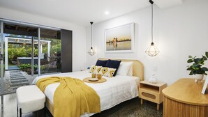 Quarto moderno com cama, mesa de cabeceira e vista para um jardim.