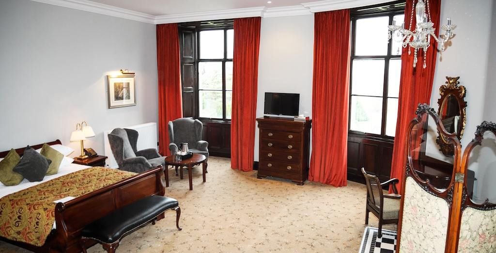 A hotel room with a bed, a desk, a chair, a television, and a dresser.