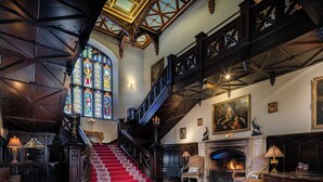A grand staircase with red carpet leading to a high ceiling with wooden beams. - Markree Castle (Collooney)