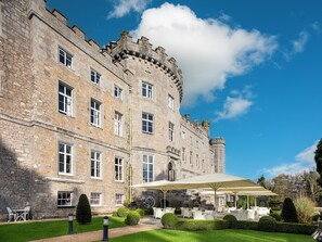 A historic stone building with multiple windows and a courtyard with outdoor seating.