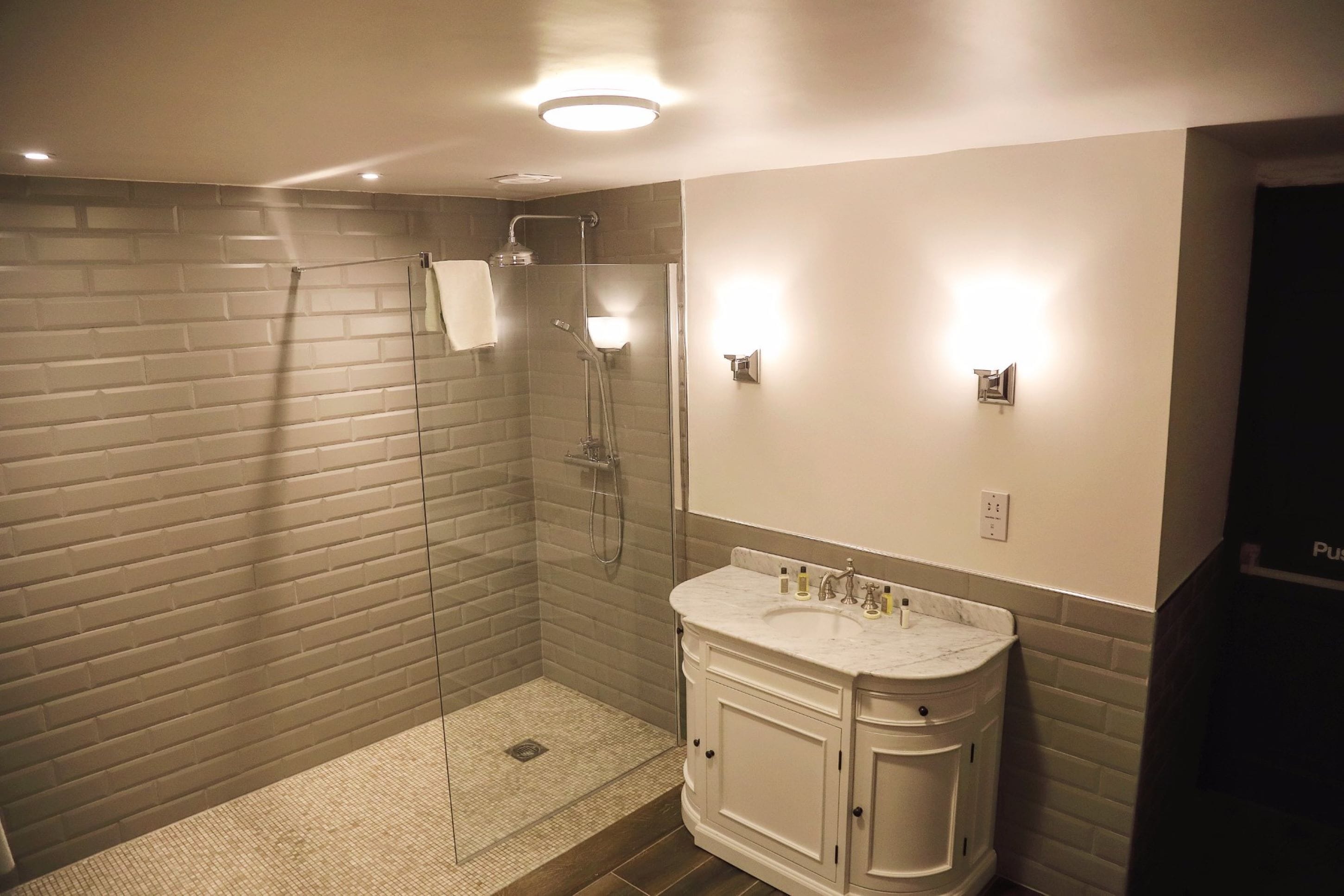 A modern bathroom with a glass-enclosed shower, a marble sink, and a vanity with cabinets.