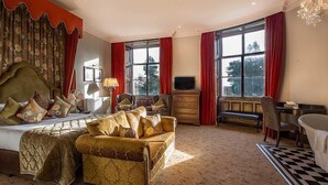 A spacious bedroom with a large bed, a sofa, a TV, and a desk.