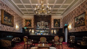 A bar area with a chandelier, bar counter, and seating.